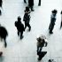 Person standing alone in busy place with people walking all around them