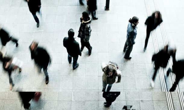 Person standing alone in busy place with people walking all around them