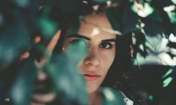 Woman standing behind tree leaves